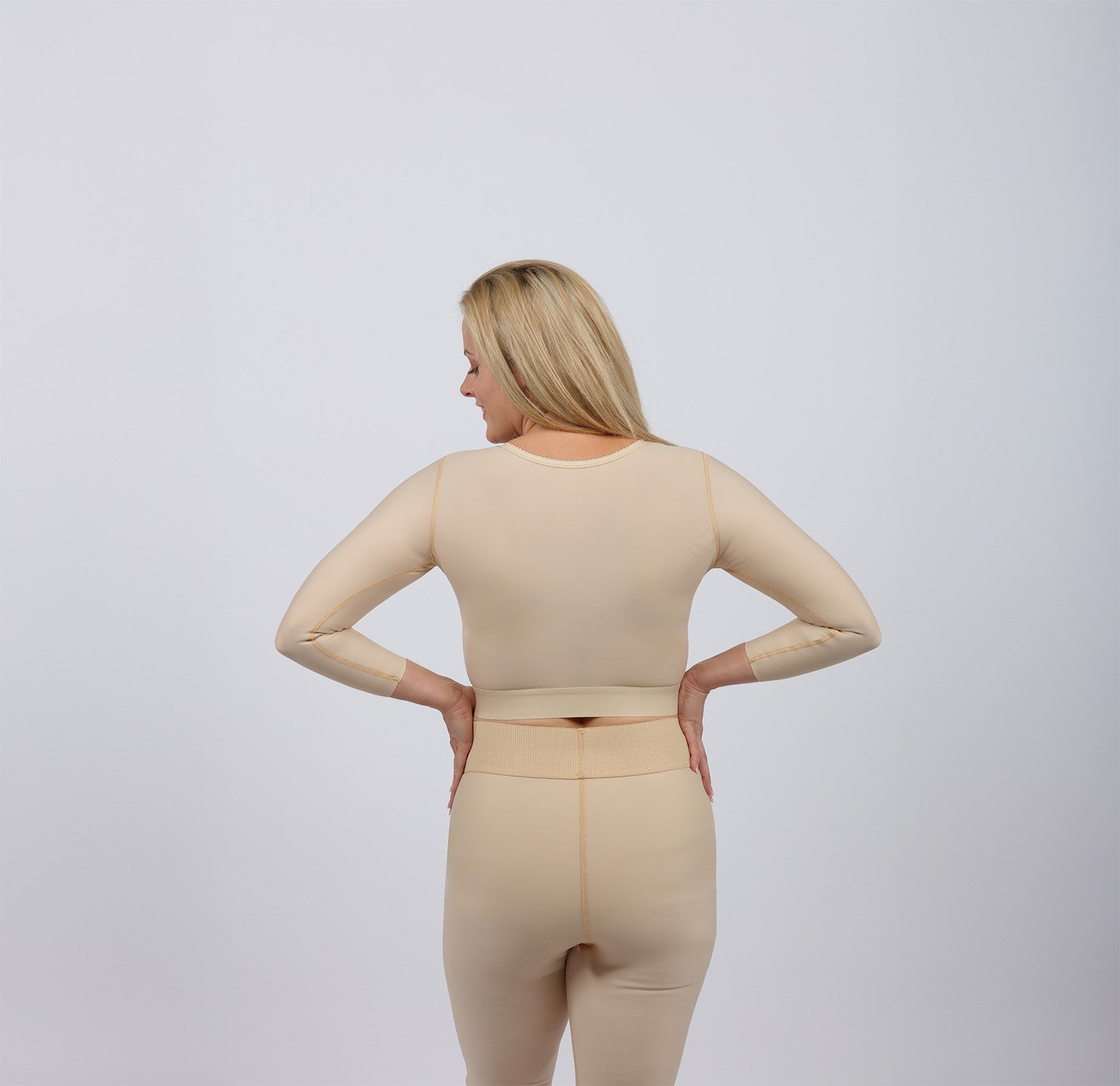 Woman shown from behind in a beige post-surgery compression garments
