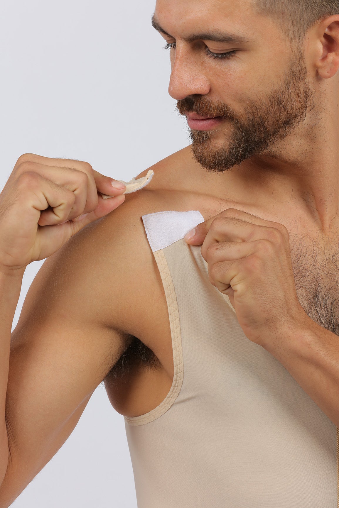 Man fastening his beige compression vest shoulder strap, close-up view