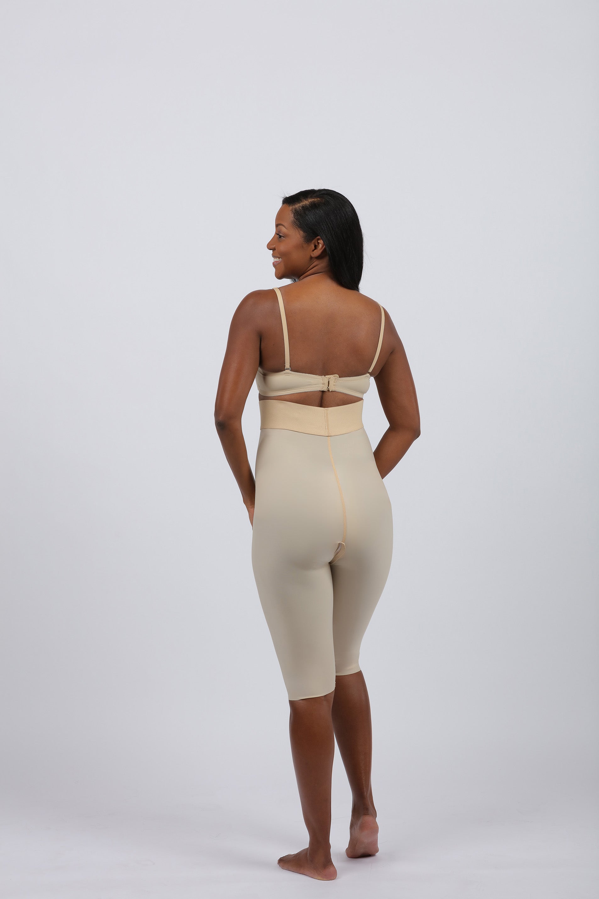 Woman shown from behind in a beige post-surgery compression garment